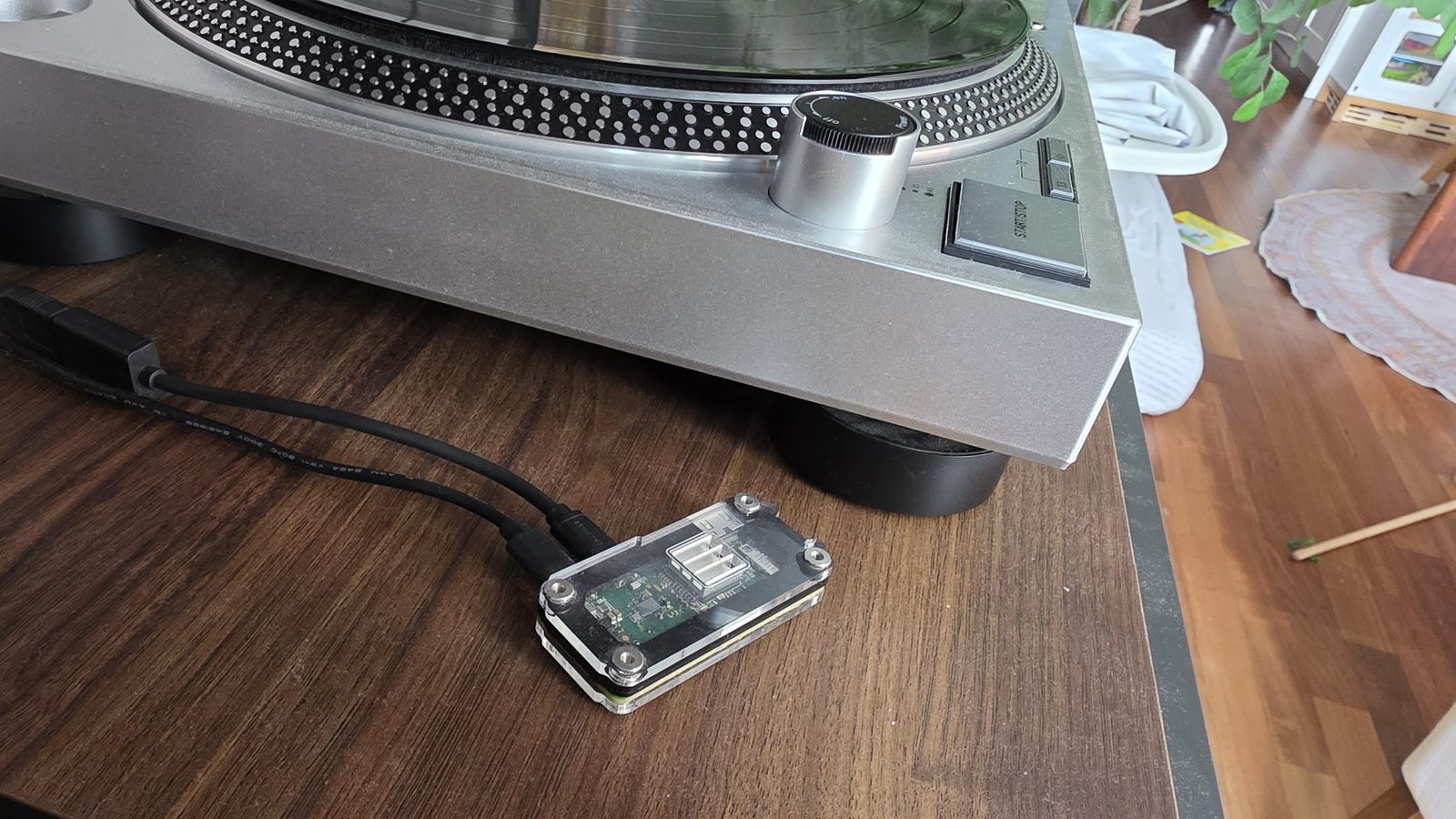A Raspberry Pi Zero in a clear case, wired to a silver turntable